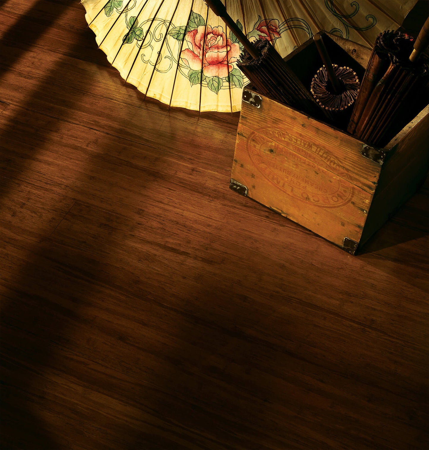 Wooden box with pencils on a wooden surface, illuminated by a lamp with floral design.