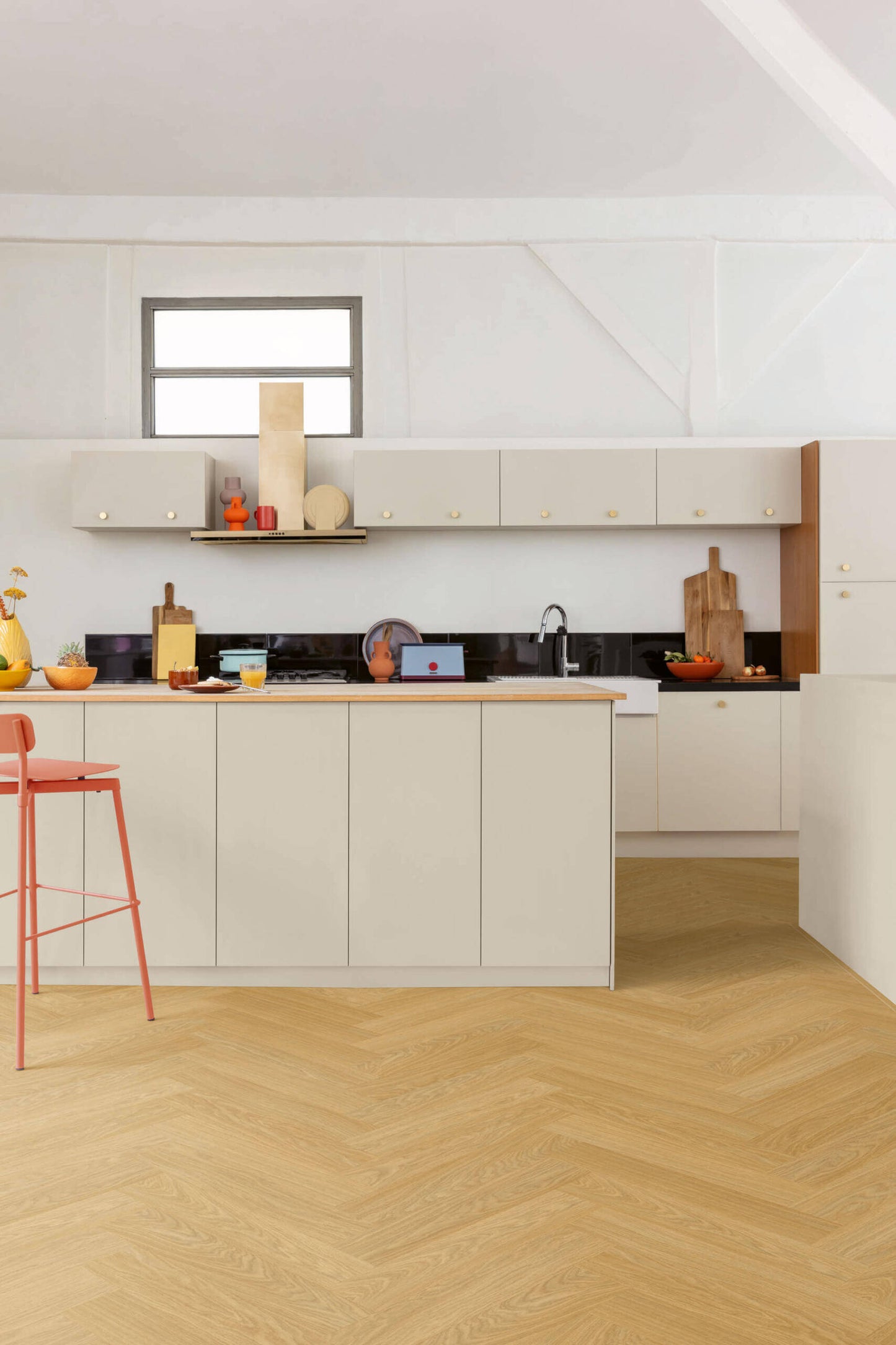 Modern kitchen with white cabinets, wooden floor, and red bar stool.