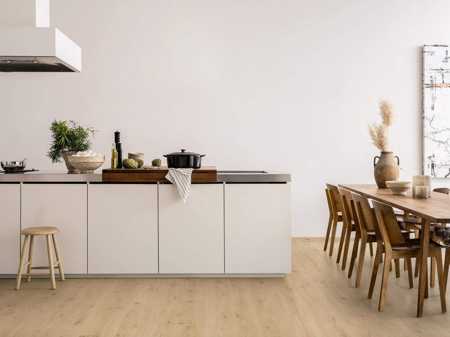 Modern kitchen with white cabinets, wooden dining table, and chairs.