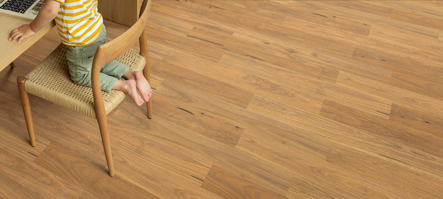 Person sitting on a chair at a wooden table with a wooden floor.