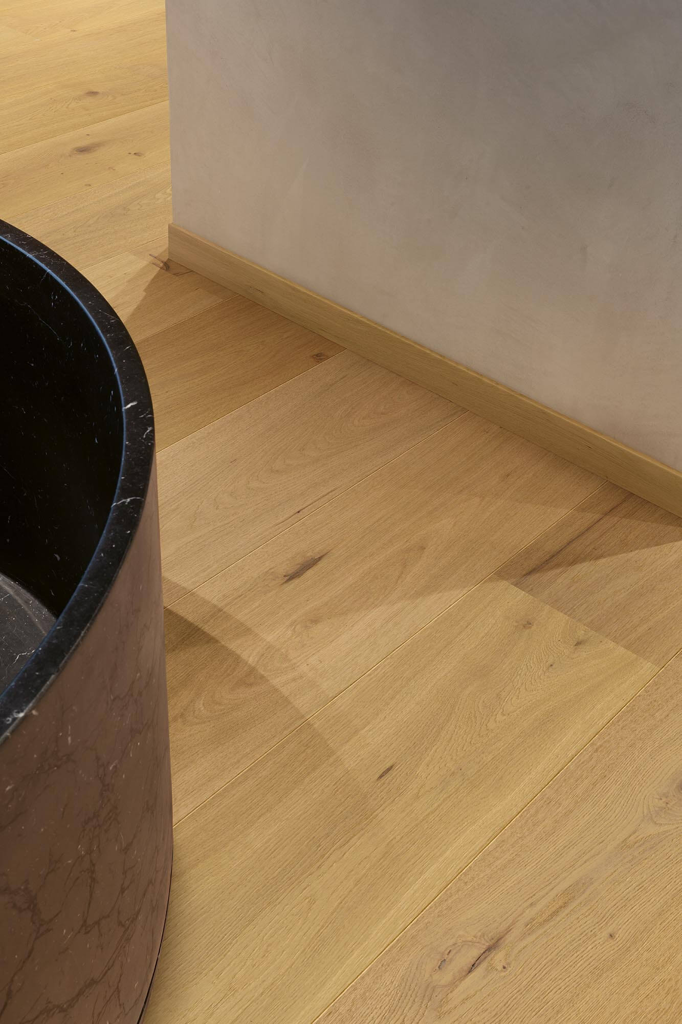 Close-up of a wooden floor with a corner and a black cylindrical object.
