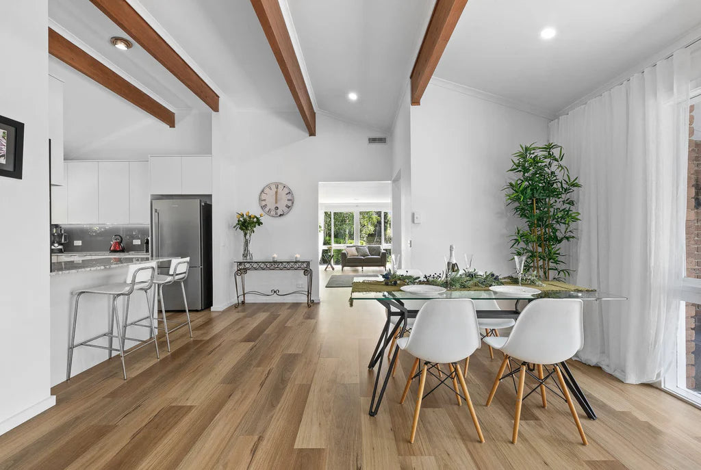 Modern kitchen and dining area with wooden floors and white walls.