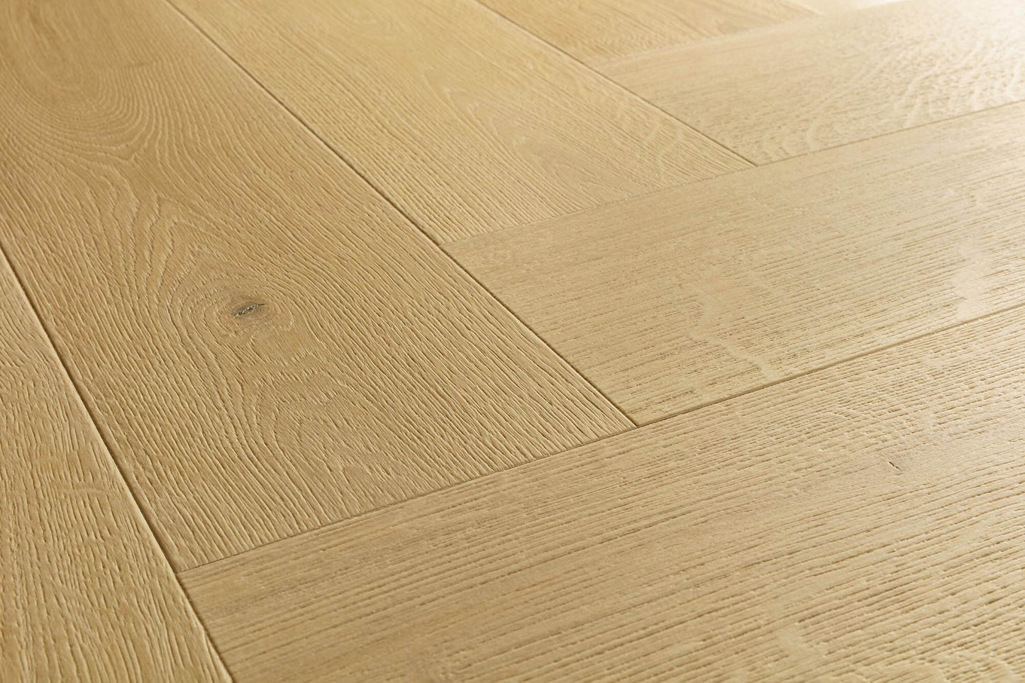 Light oak wood flooring planks arranged in a herringbone pattern, showing natural wood grain and a subtle knot.