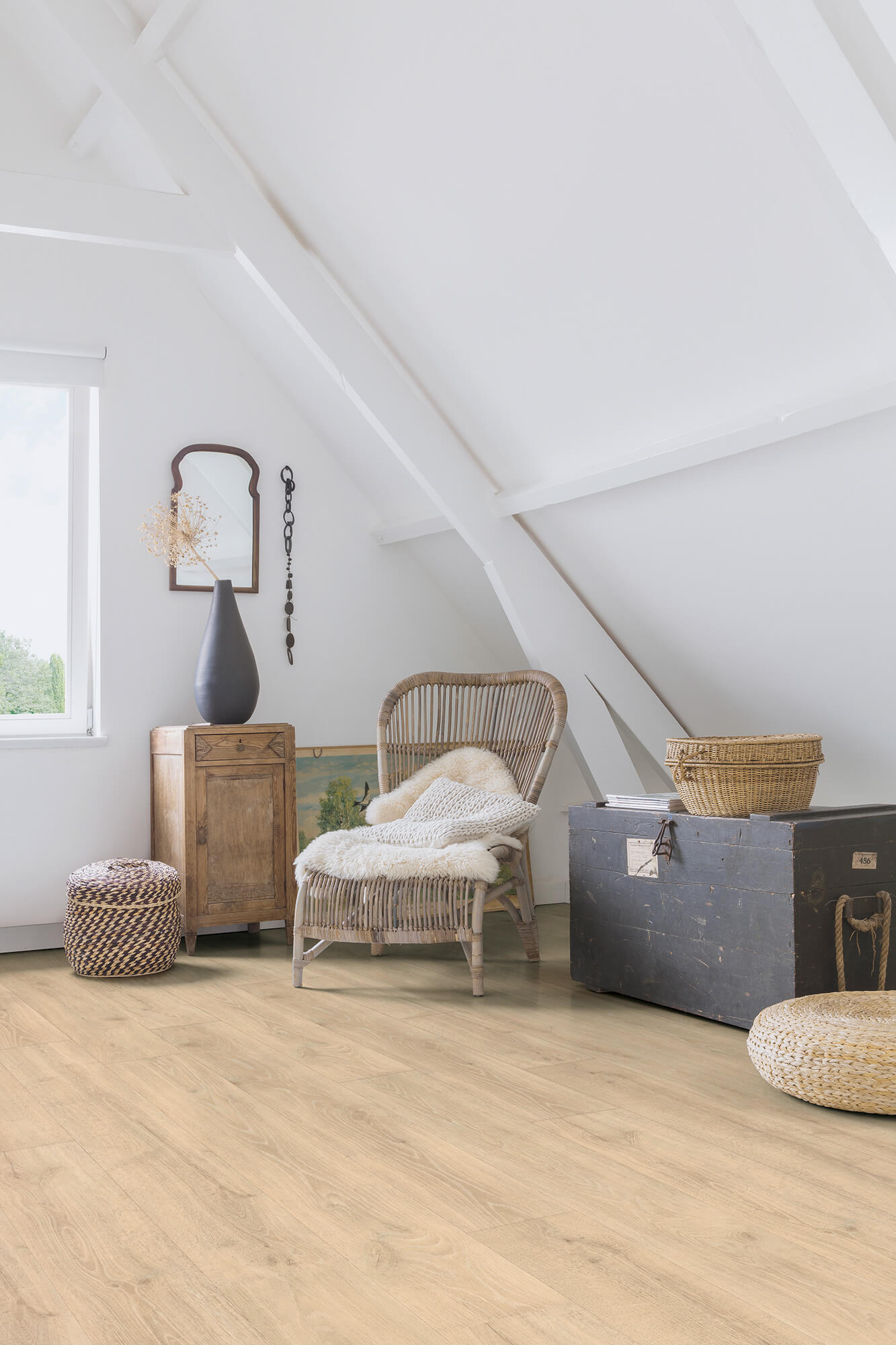 Attic room with wooden floor, wicker chair, and storage trunk.