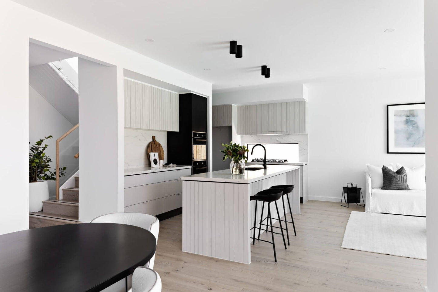 Modern kitchen and living room with white walls and black fixtures