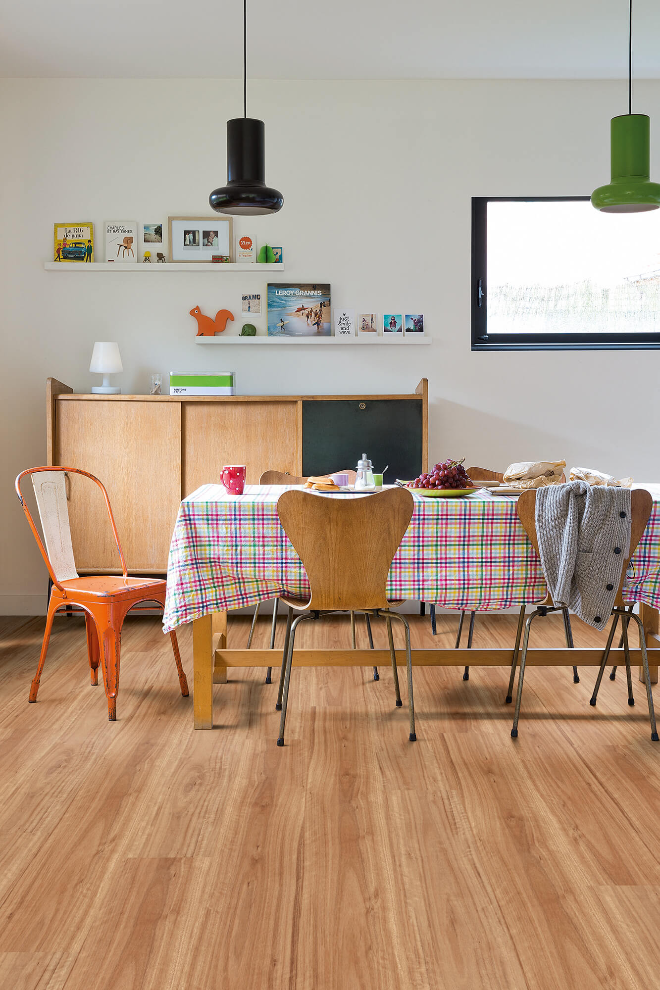 Dining room with wooden floor, table, chairs, and a wall with shelves and a TV.