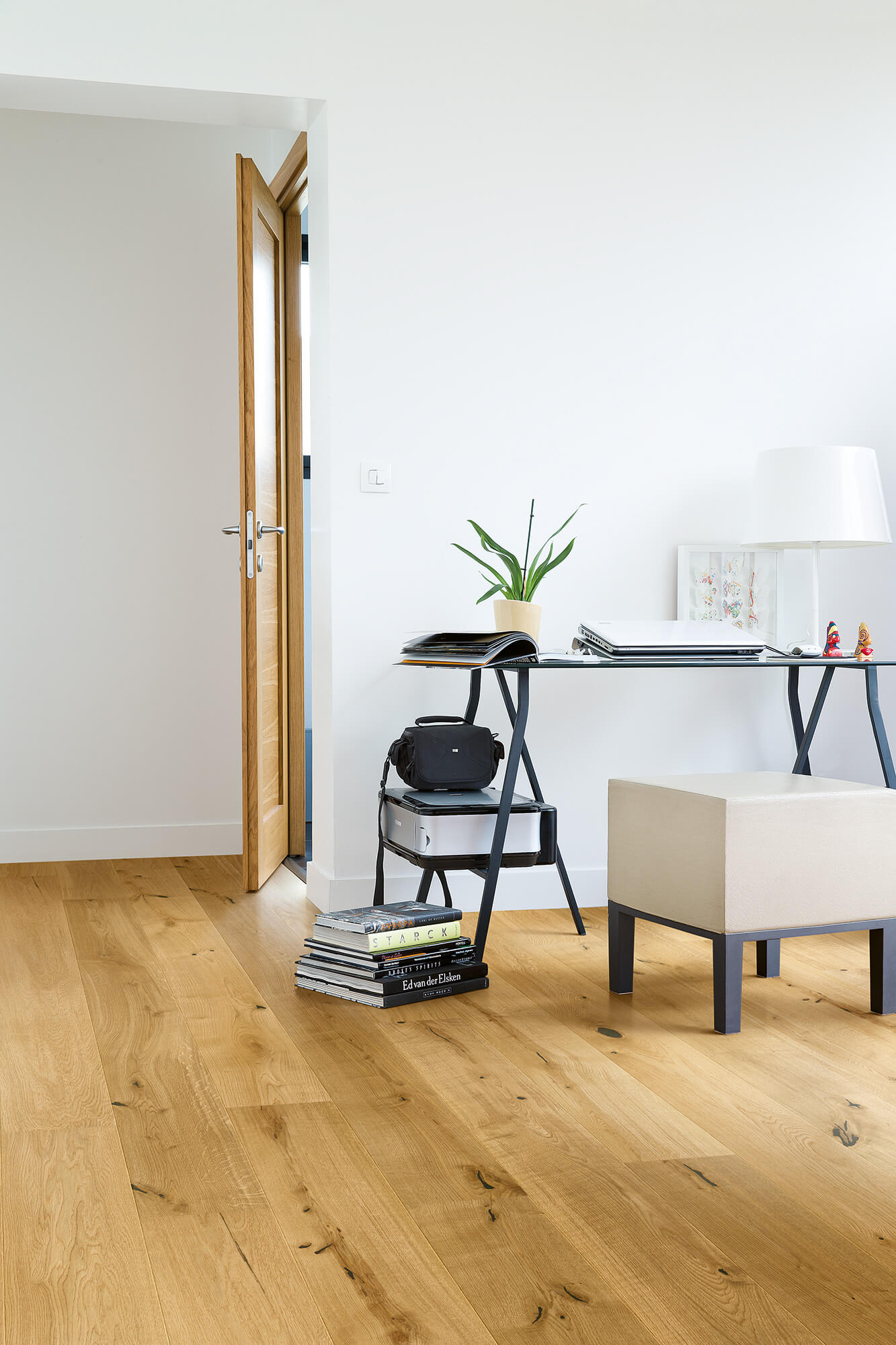 Modern home office with wooden flooring, desk, and decor.