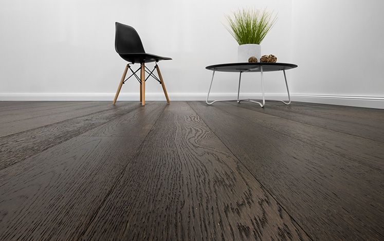 Wooden floor with a black chair and table against a white wall