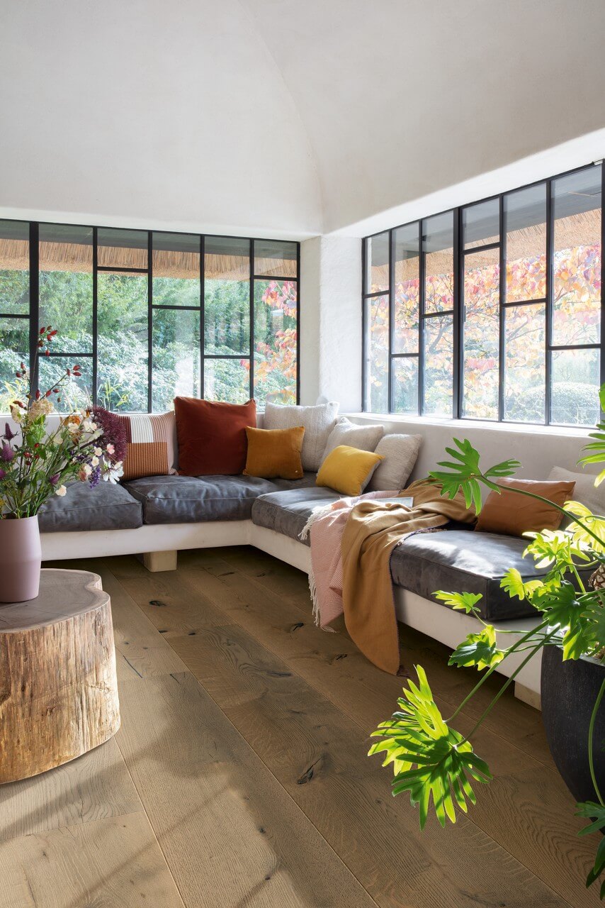 Modern living room with a sectional sofa, colorful cushions, and large windows.