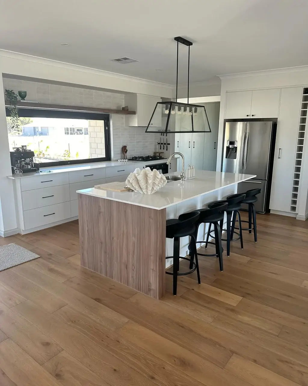 Modern kitchen with island, stools, and stainless steel appliances.