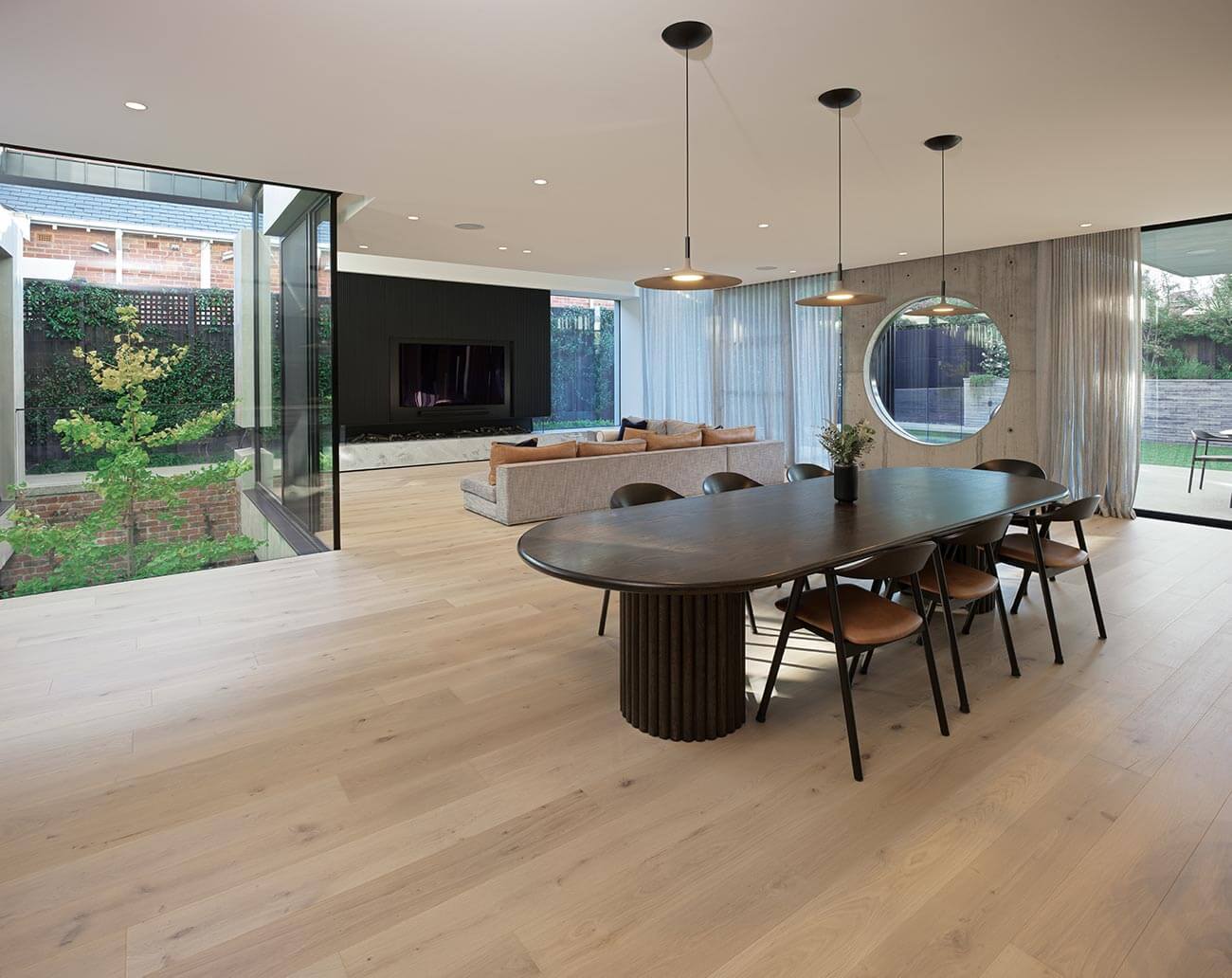 Modern dining area with a round table and chairs in a well-lit room with large windows.