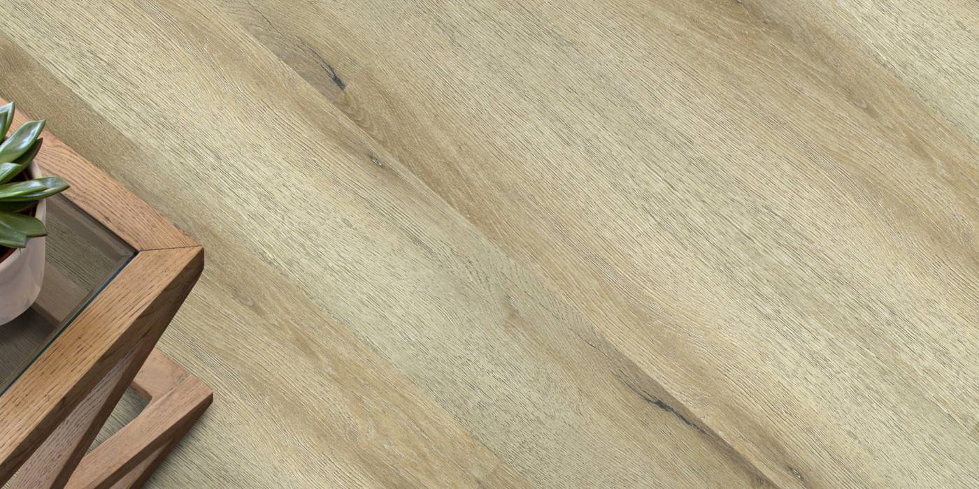Close-up of a wooden floor with a plant and small table in the corner.
