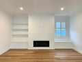 Empty room with white walls, wooden floor, and a fireplace.