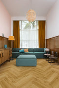 Modern living room with teal sectional sofa, wooden floor, and large window.