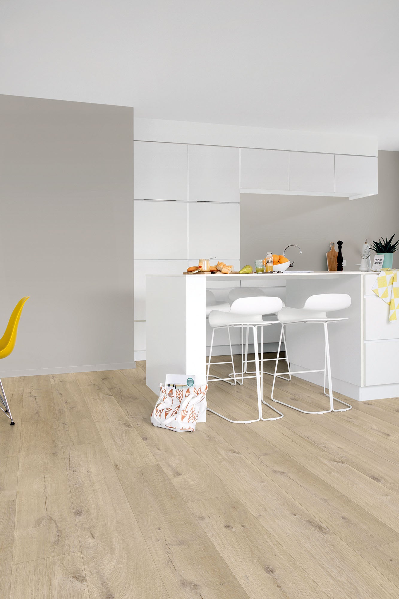 Modern kitchen with light wood flooring and white cabinets.