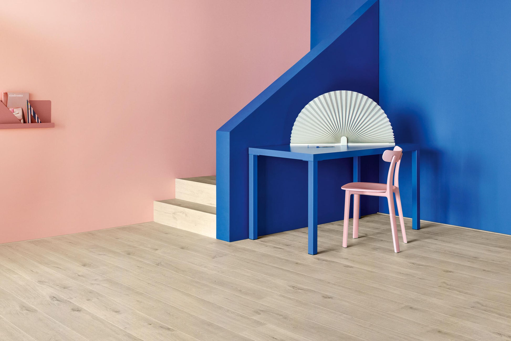 Modern interior with a blue wall, pink chair, and white table.