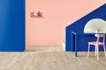 Modern interior design with pink and blue walls, a desk, and chair.