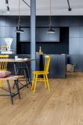 Modern kitchen with dark blue cabinets, wooden floor, and yellow chairs.