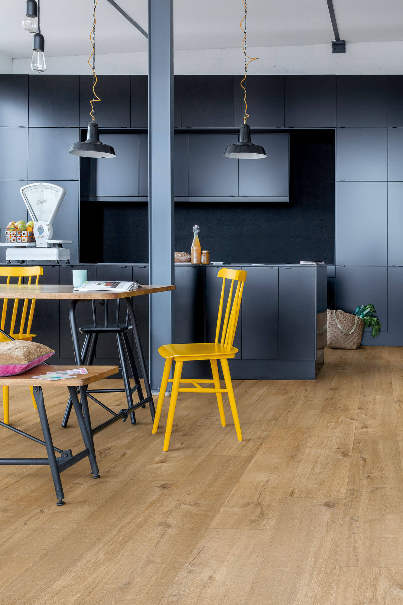 Modern kitchen with dark blue cabinets, wooden floor, and yellow chairs.