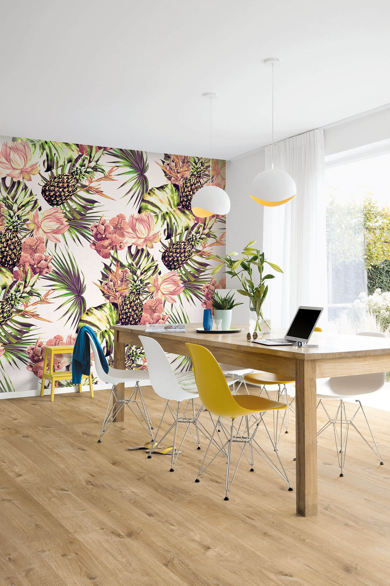 Modern office with colorful floral wall mural, wooden desk, and colorful chairs.