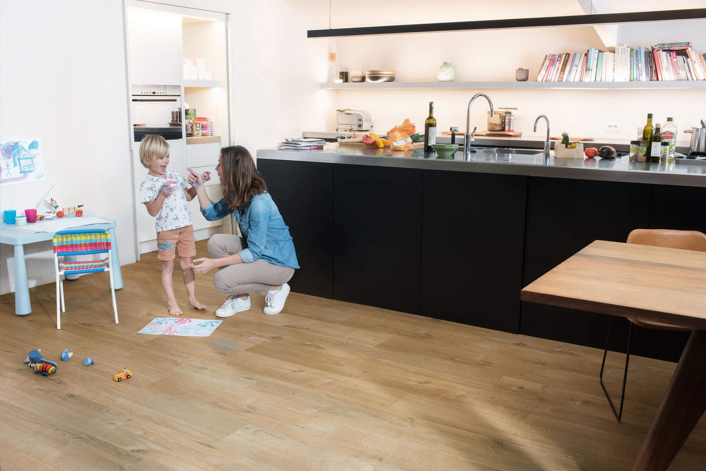Woman and child in a modern kitchen with wooden flooring
