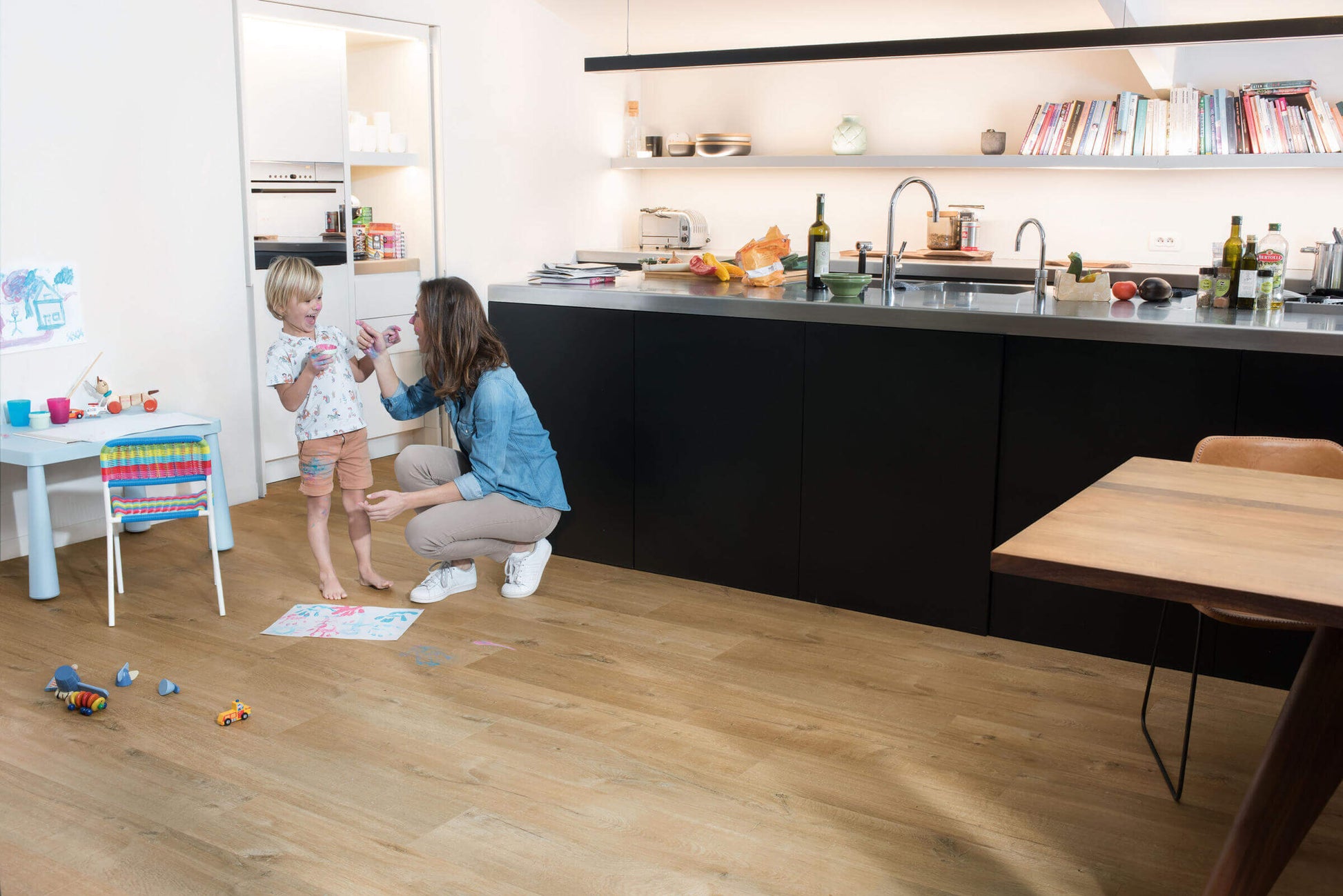 Woman and child in a modern kitchen with wooden flooring