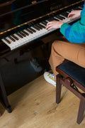 Person playing a piano with a focus on hands and keyboard