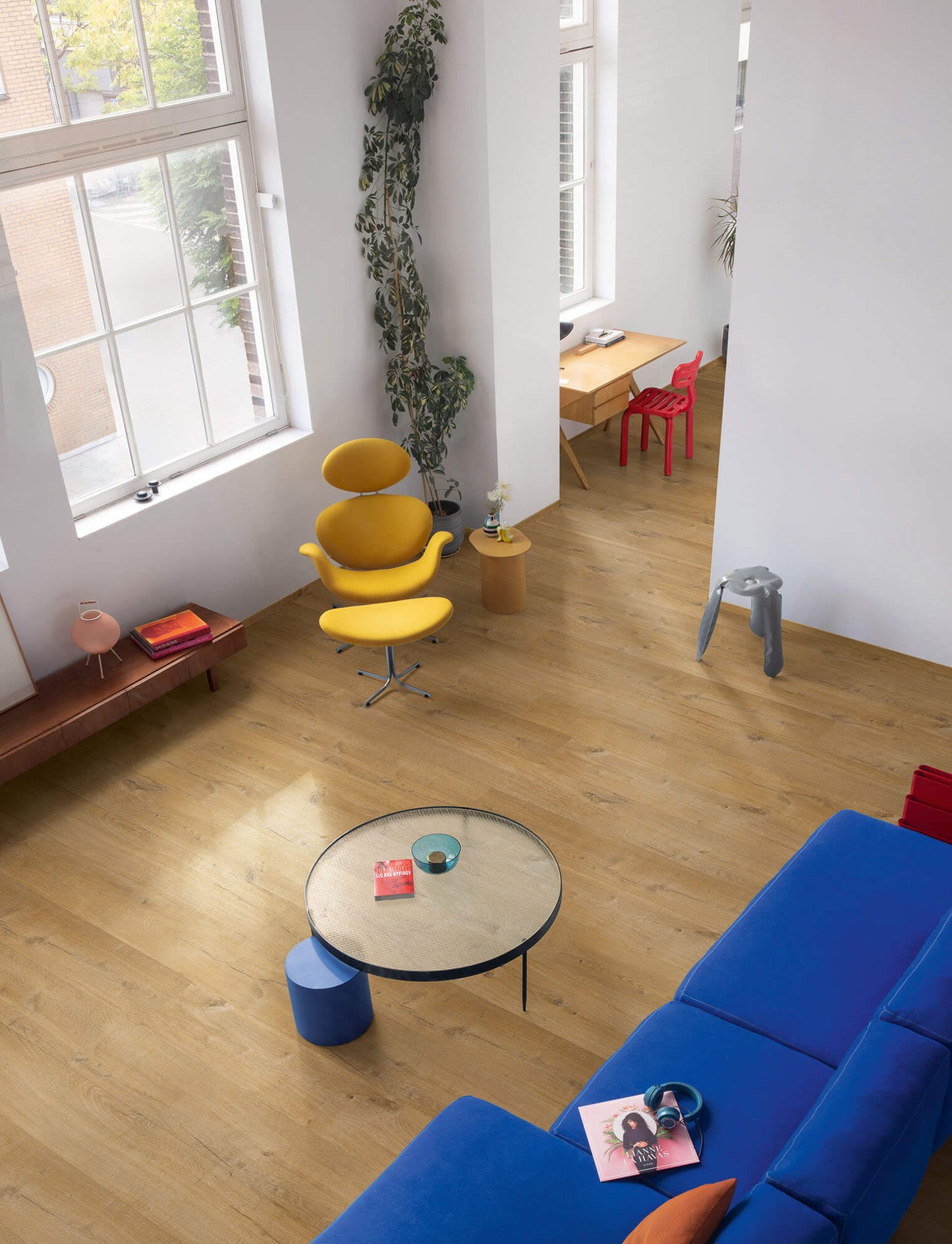 Modern living room with a blue sofa, yellow chair, and round coffee table.