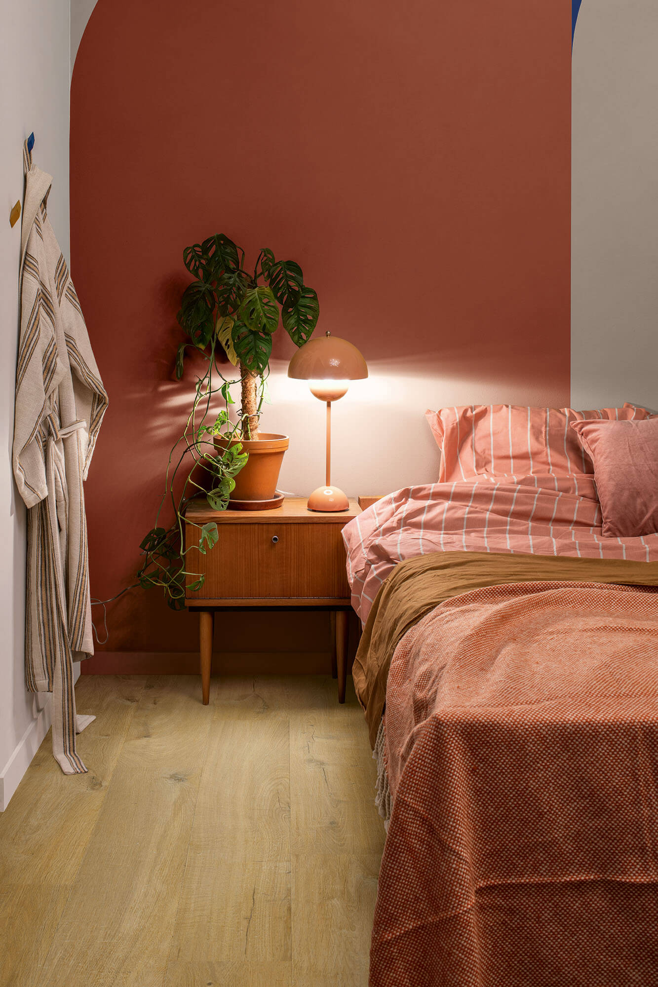 Bedroom with pink walls, wooden nightstand, and pink bedding.