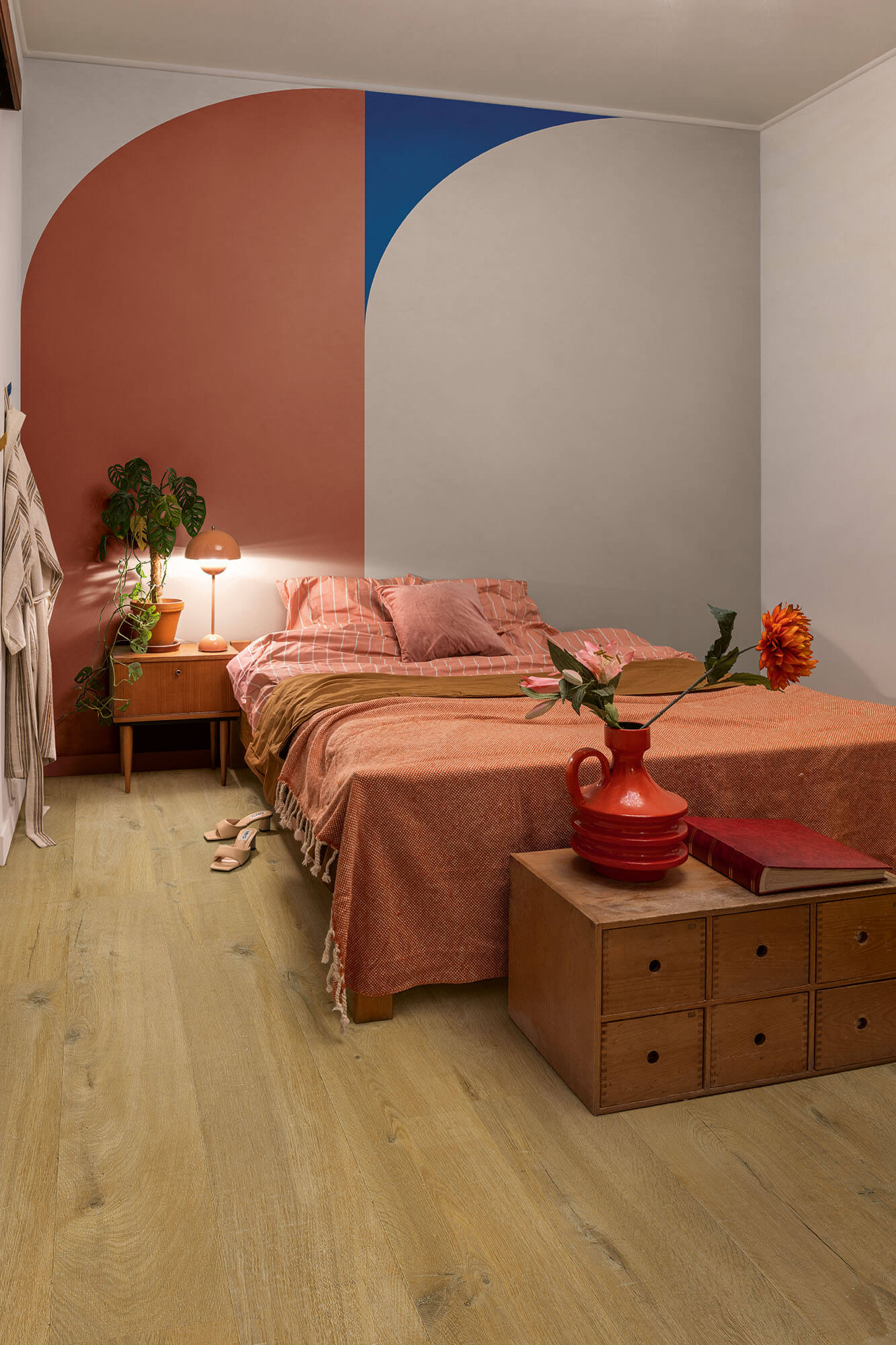 Bedroom with a colorful wall, bed, nightstands, and decor items.