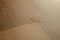 Wooden floor with a small cluster of gold beads on it