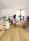 Living room with wooden flooring, white walls, and people interacting.