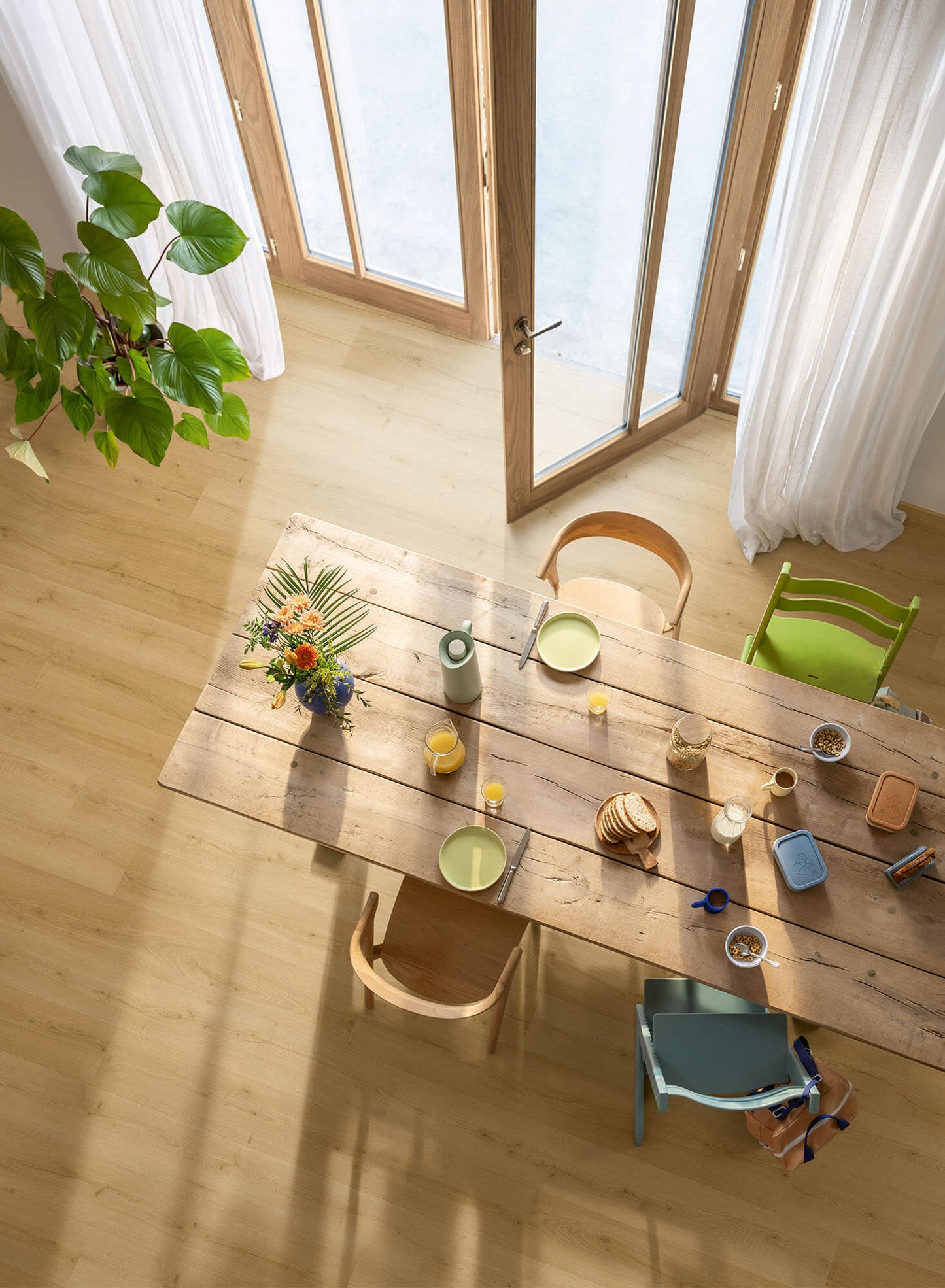 Dining area with a wooden table, chairs, and decorative items in a bright room.