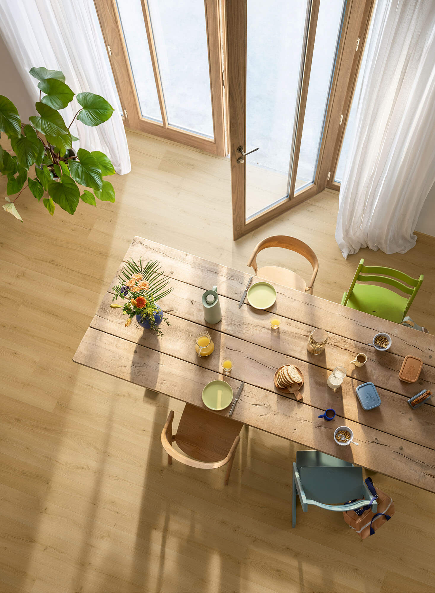 Dining area with a wooden table, chairs, and decorative items in a bright room.