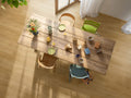 Wooden dining table with chairs and various items on a wooden floor.