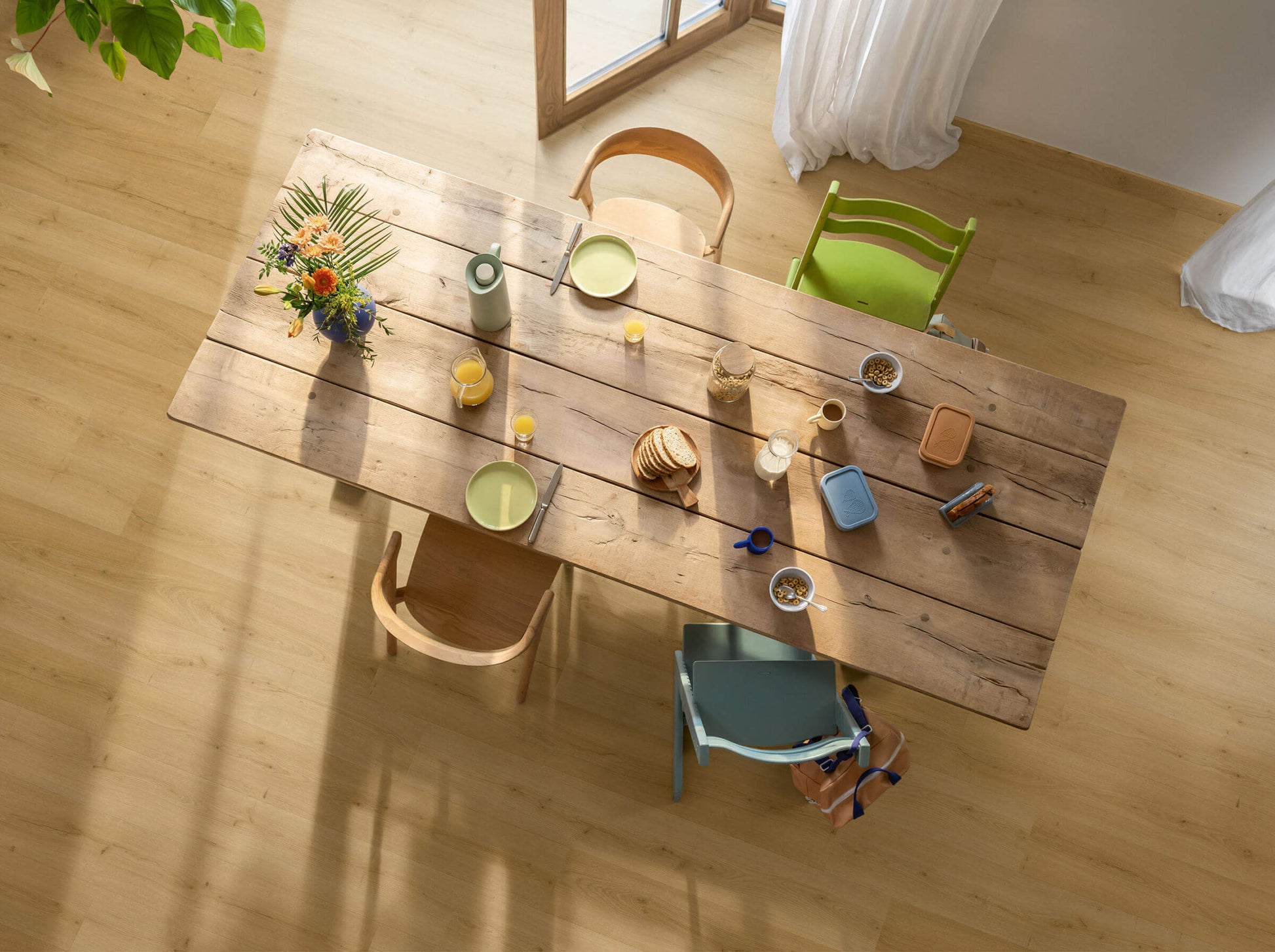 Wooden dining table with chairs and various items on a wooden floor.
