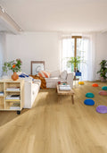 Modern living room with light wood flooring, white walls, and colorful decor items.