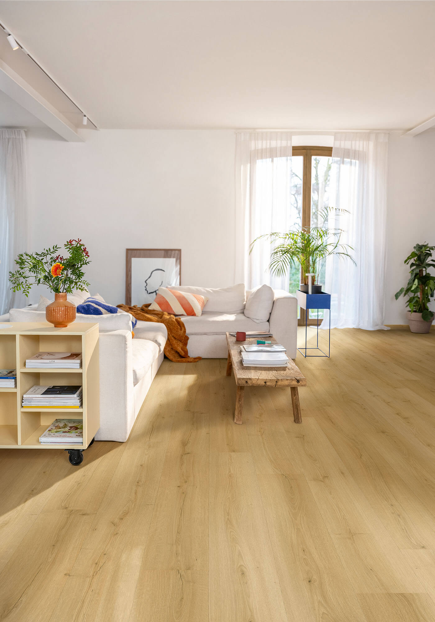 Modern living room with wooden flooring, white walls, and decorative elements.