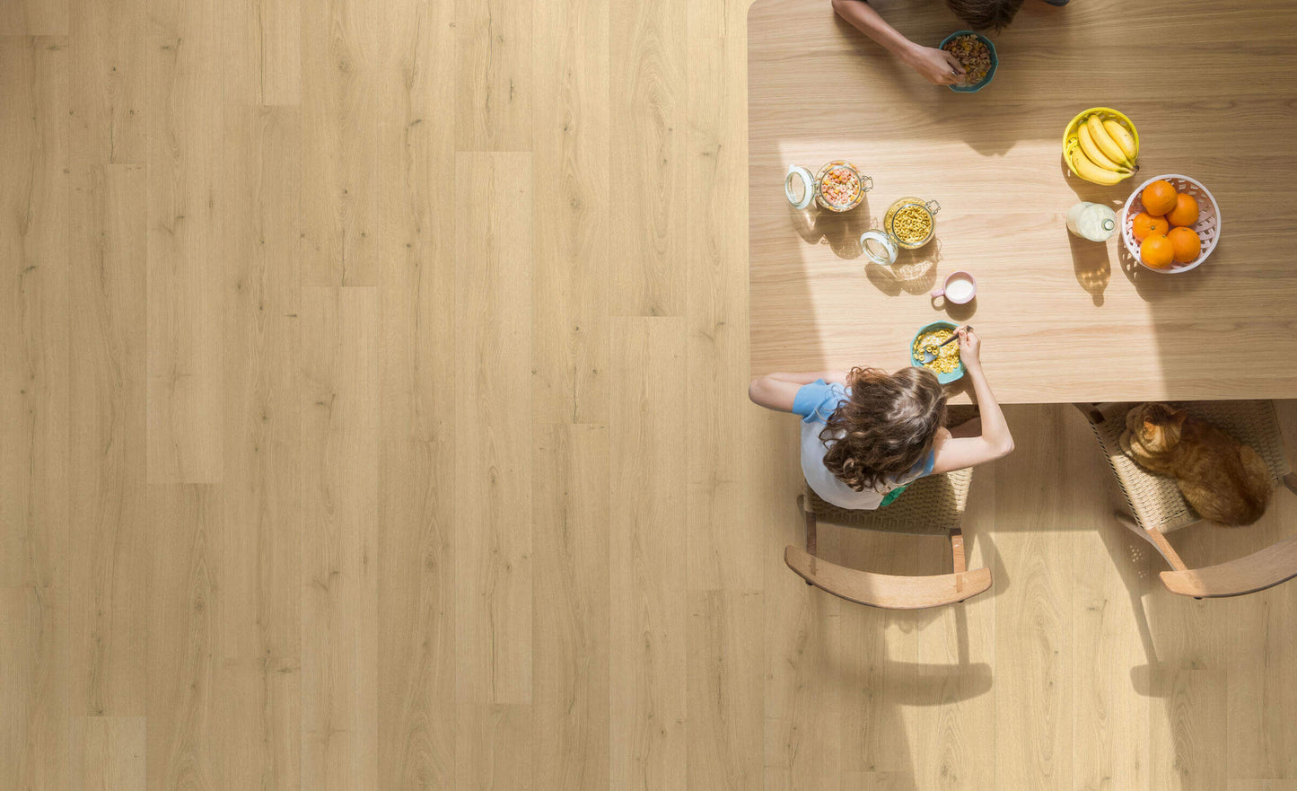 Top-down view of a person sitting at a wooden table with food and drinks.