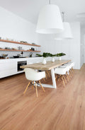 Modern kitchen with wooden dining table and chairs, white pendant lights, and open shelves.