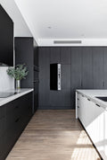 Modern kitchen with black and white cabinetry, wooden floor, and white ceiling.