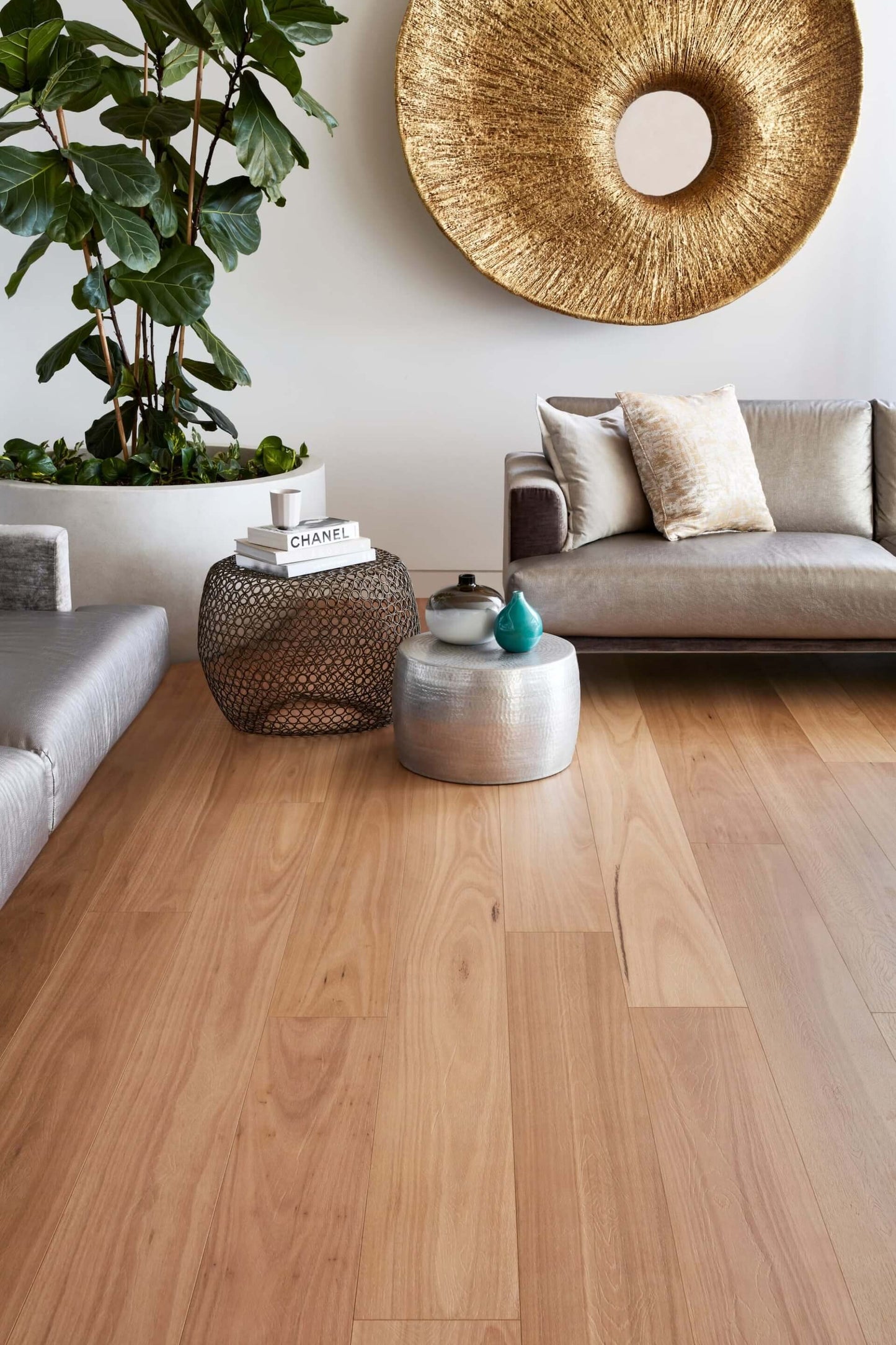 Modern living room with wooden flooring, gray sofa, and decorative items.