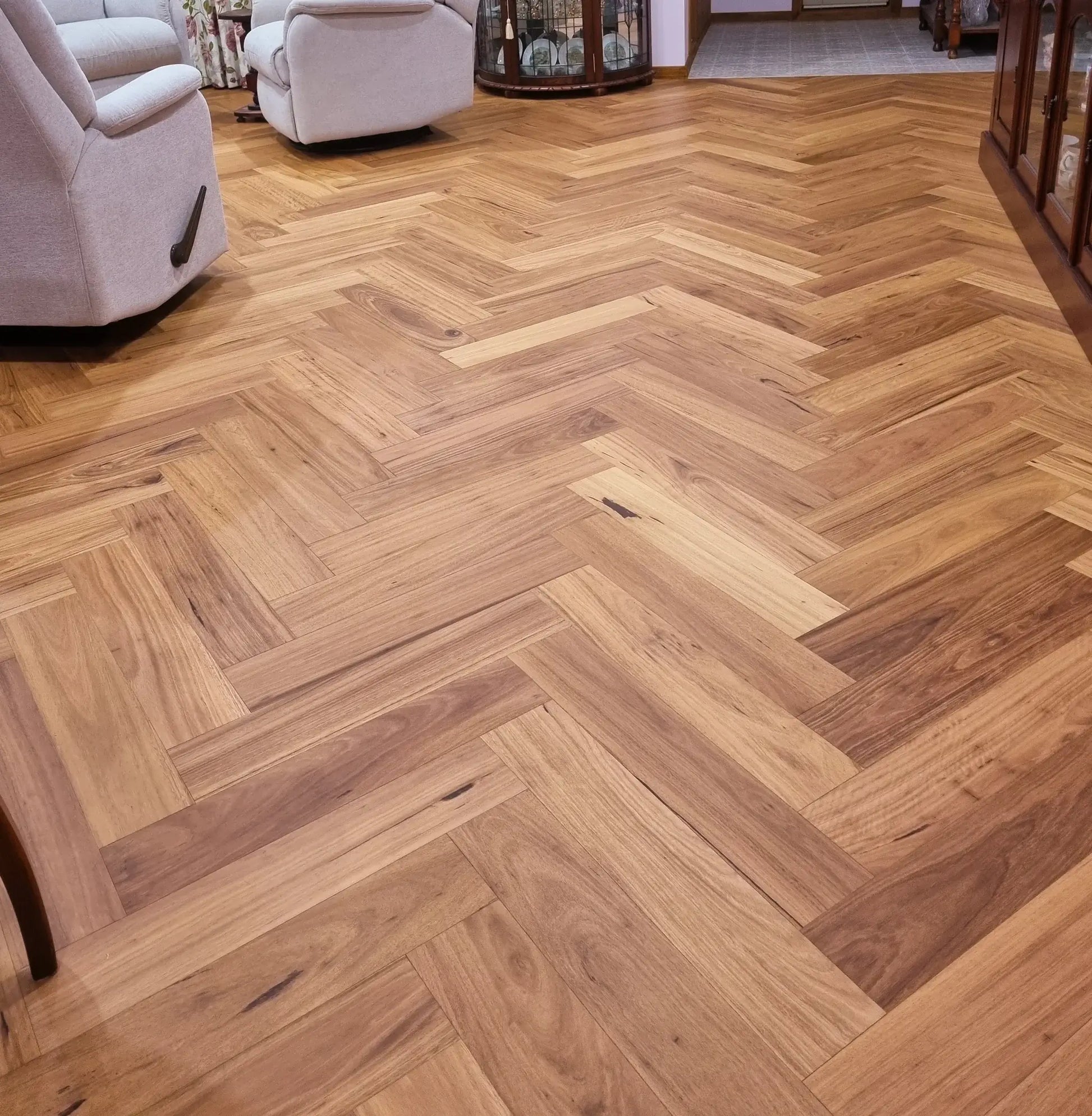 Wooden floor with herringbone pattern in a room with furniture.