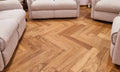 Wooden floor with herringbone pattern in a room with beige sofas.