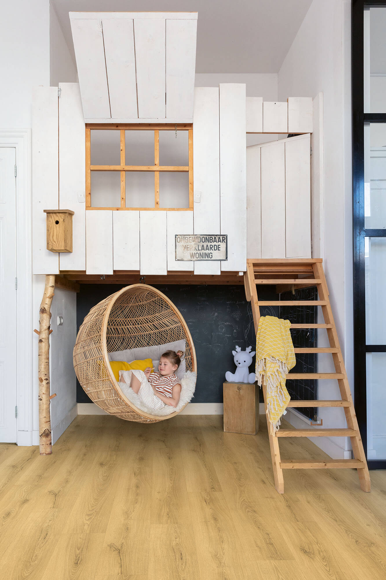 Children's room with a loft bed, wicker chair, and ladder.