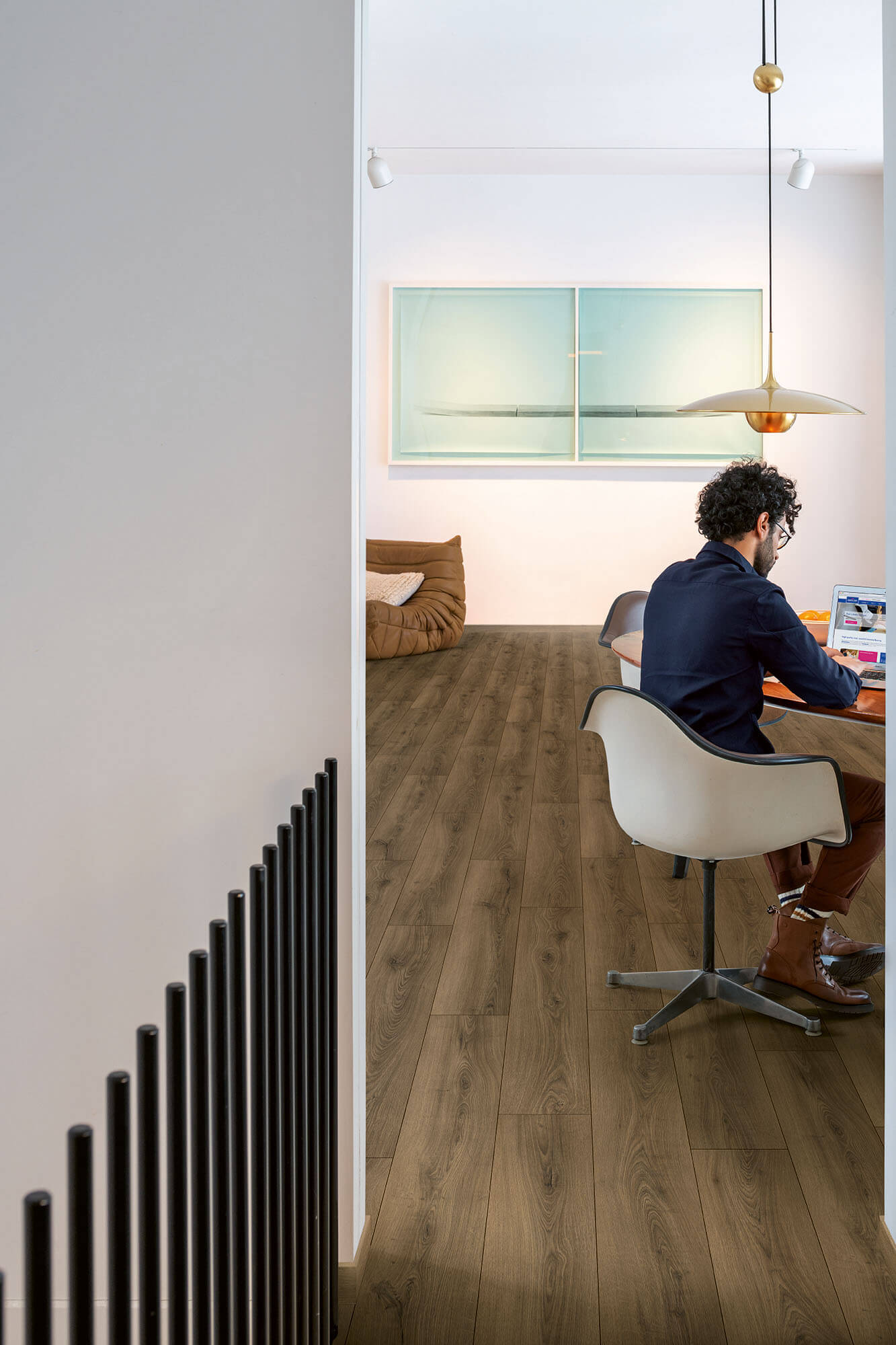 Person working at a desk in a modern office with wooden flooring.