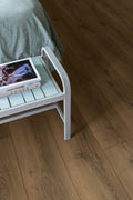 Small white side table with a green surface next to a bed on a wooden floor.