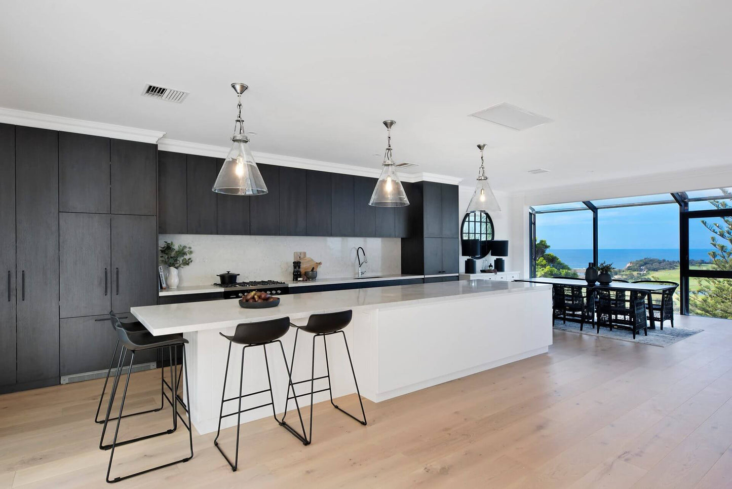 Modern kitchen with black and white design, including a kitchen island and stools.