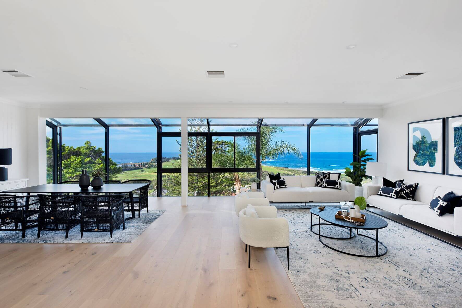 Modern living room with large windows overlooking a scenic view of trees and water.