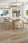 Modern dining room with a white table and wooden chairs in a bright, naturally lit space.